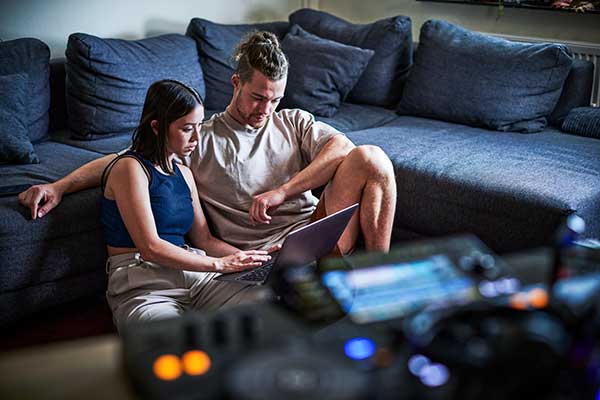 Zwei junge Personen sitzend vor dem Laptop
