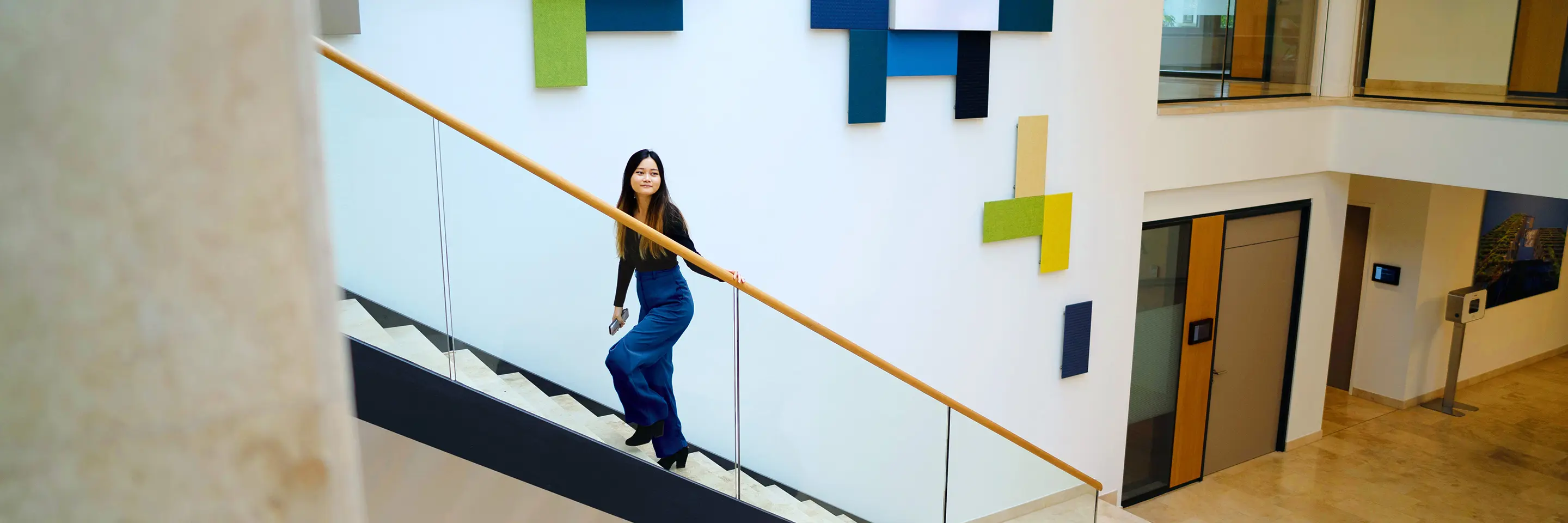 Eine weibliche Person geht eine Treppe in der Eingangshalle hinauf